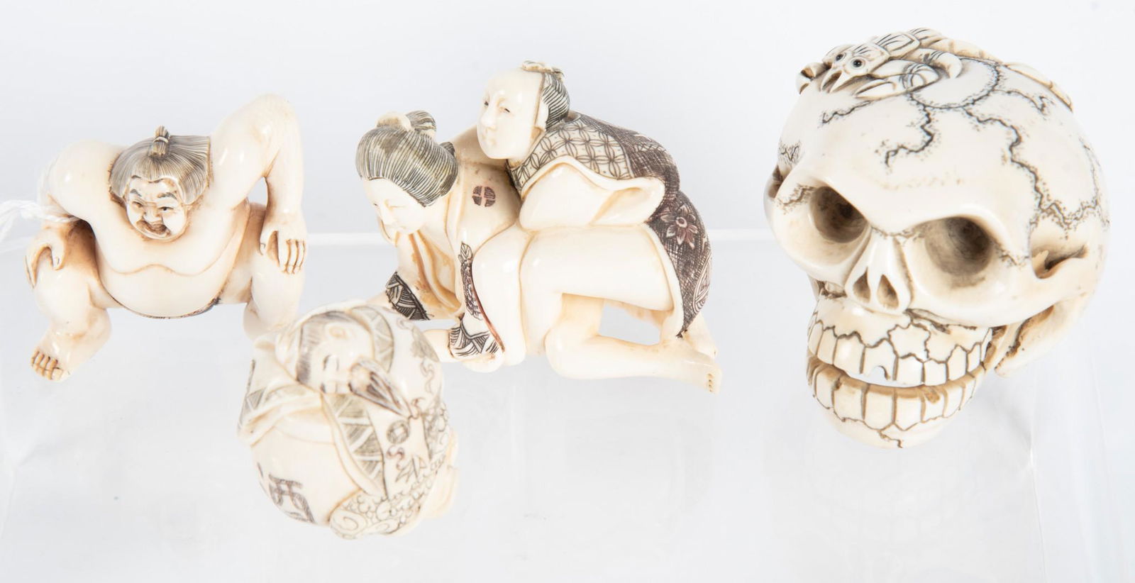 Four Japanese Carved "Bone" Objects: Four Japanese Carved "Bone" ObjectsGrouping consists of 2 carved netsukes, an erotic carving, and a memento mori carving of a skull, all signed.