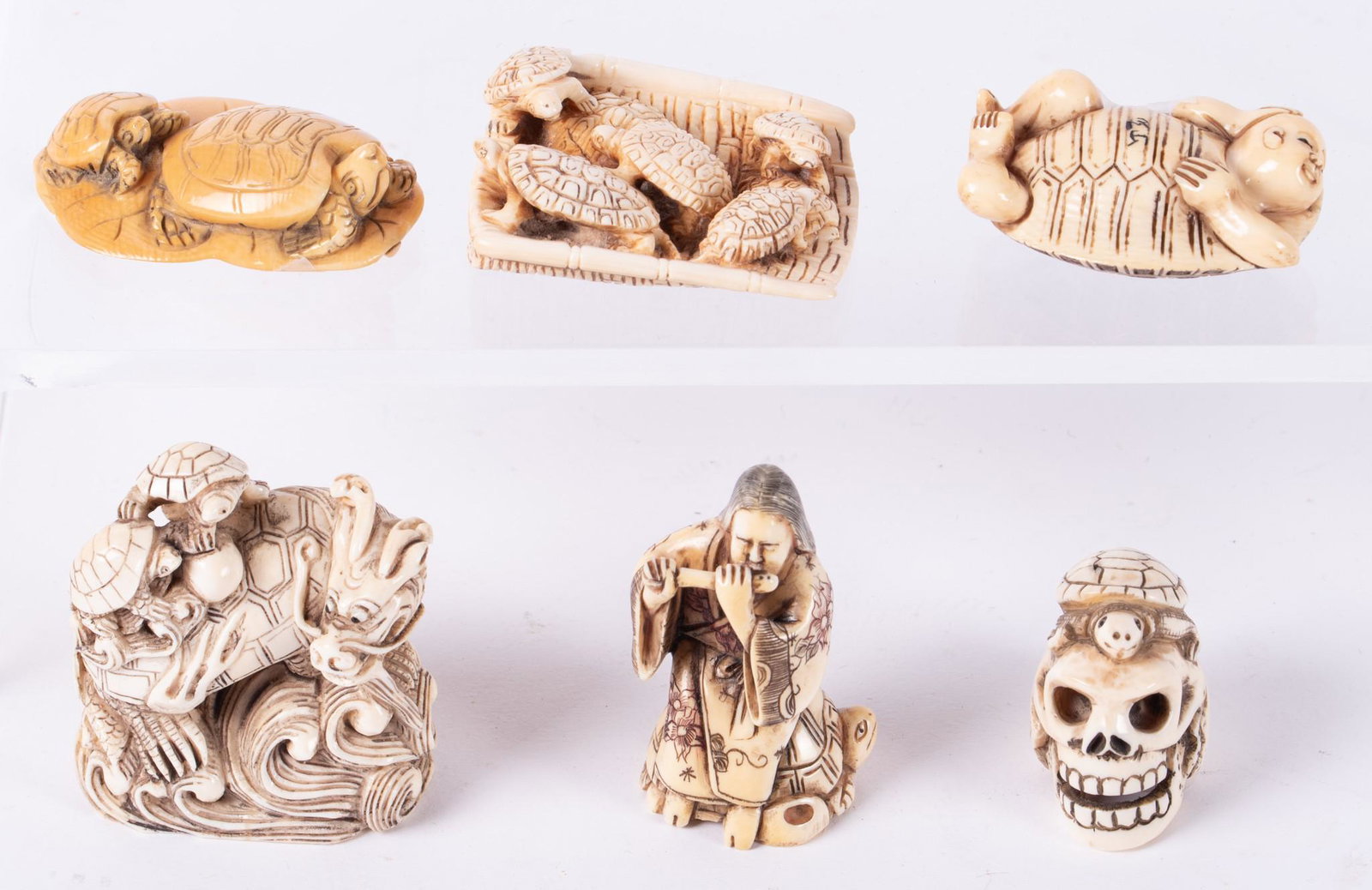 A Collection of Six Vintage Carved Japanese Netsuke: A Collection of Six Vintage Carved Japanese Netsuke Turtles Each a turtle in various form, including a turtle on a skull, turtles riding on a raft, a musician on a turtle, turtles on a lotus leaf, a d