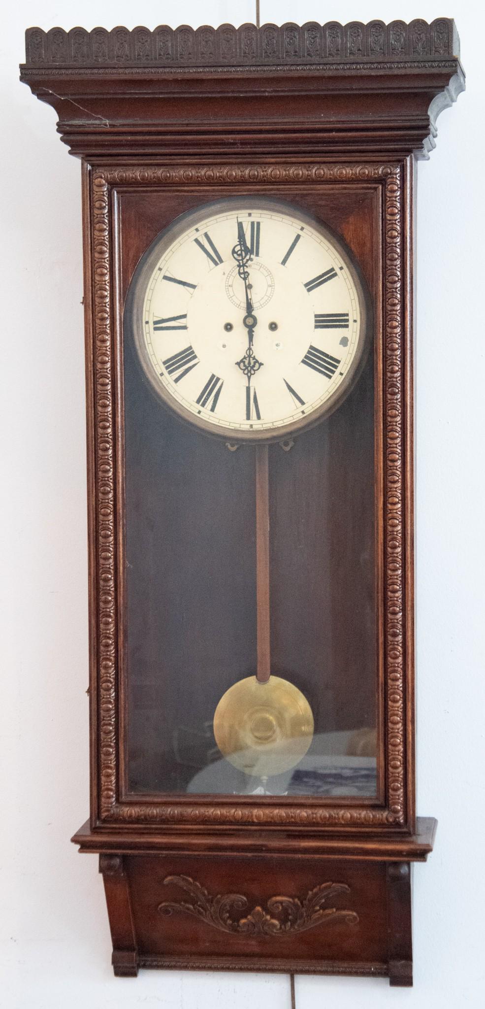 Antique American Wall Clock: Antique American Wall ClockShaped cornice with a circular dial below with gilt highlights, Roman Numeral chapter ring and second hand dial within a glazed door and a slanted panel with scroll work.50