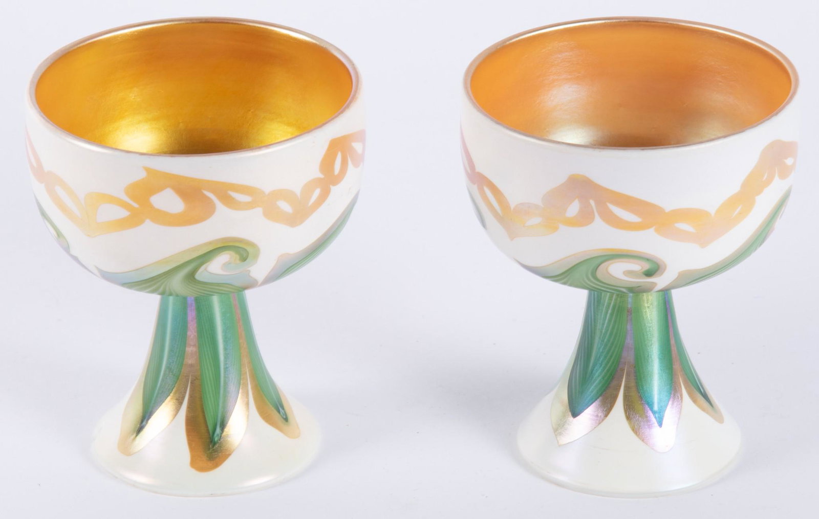 Pair of Quezal Art Glass Wine Goblets: Pair of Quezal Art Glass Wine Goblets The two goblets with pulled green and gold feather designs on a white ground, the bowl in a deep gold aurene color. Signed to base, Quezal. 3 3/4" tall