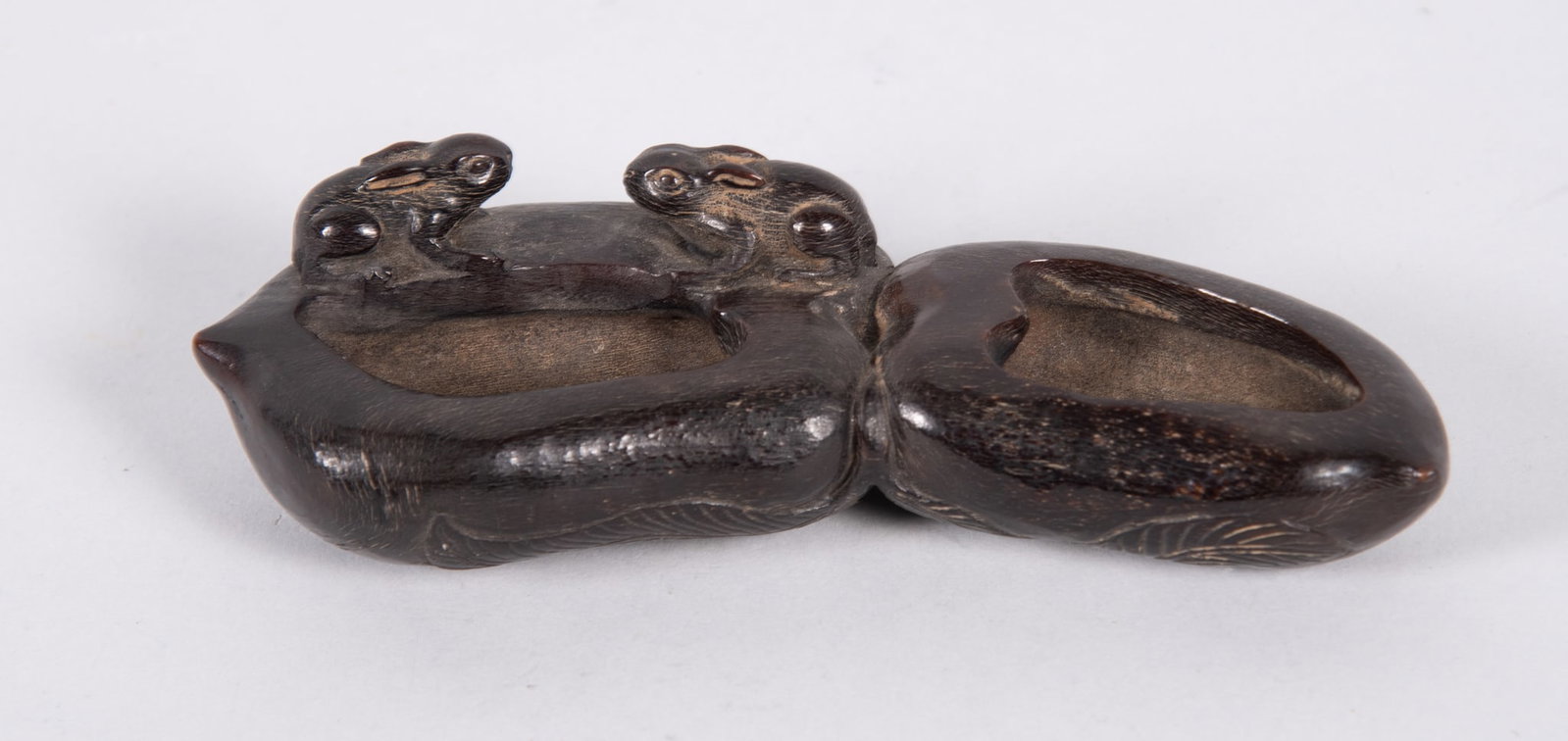 An Unusual Chinese Blackwood Double Brush Wash Pot: An Unusual Chinese Blackwood Double Brush Wash Pot China, the elongated wash pot, carved in blackwood depicting two rabbits sitting atop lotus. 6 inches long. Provenance: From the Collection of Julian