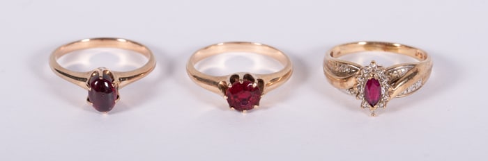 Three Gold Rings include: 14K with Garnet, 14K with Ruby, 14K and 10K with Ruby and Diamonds