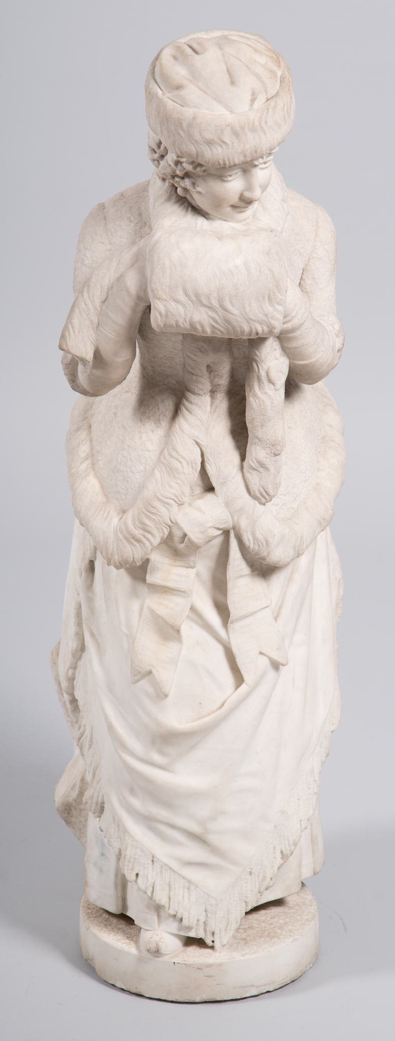 A Tall Antique Marble Sculpture, Woman in Winter Time: A Tall Antique Marble Sculpture, Woman in Winter Time A beautifully carved marble sculpture of a young woman walking in the cold, the figure in Belle Epoque style clothing, the trim of the jacket, hat