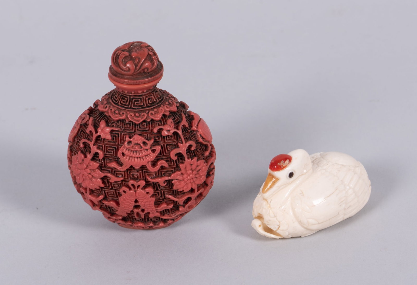 Two Chinese Snuff Bottles: Two Chinese Snuff Bottles A 2 3/4" Cinnabar style snuff bottle (likely a resin), paired with a 2" carved bone mechanical duck (as-is). Provenance: From the Collection of Juliana Yuan, Profes