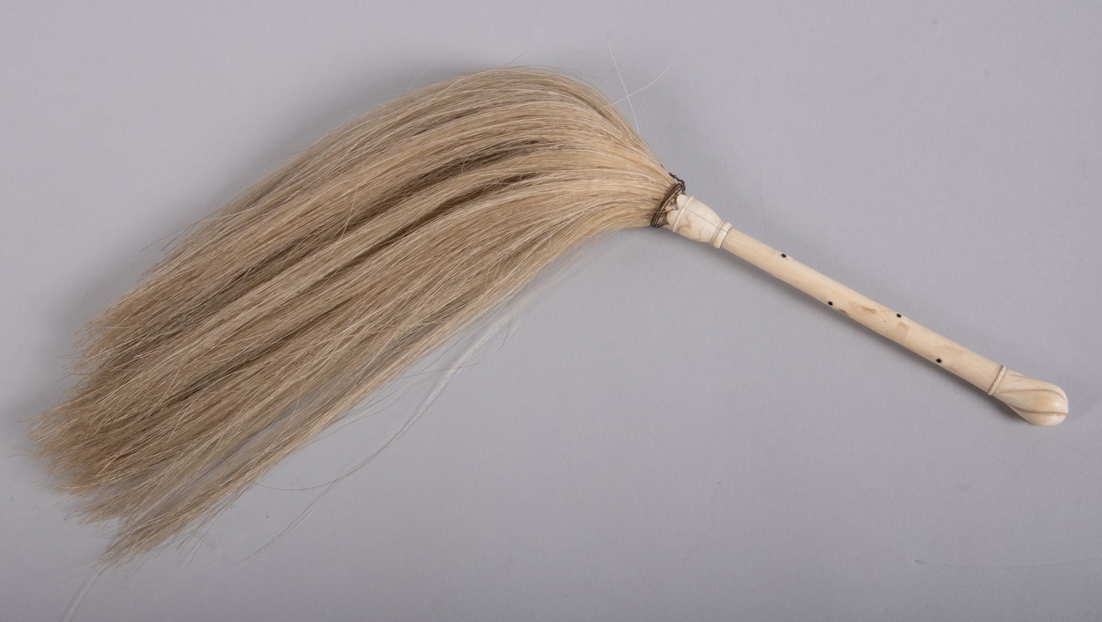 An Antique Carved Bone Handle Fly Whisk: An Antique Carved Bone Handle Fly Whisk19th century, likely Anglo-Indian, carved handle fly whisk. The horse hair mounted in to a crown shaped top, the handle with small ebony inlay to simulate a bone