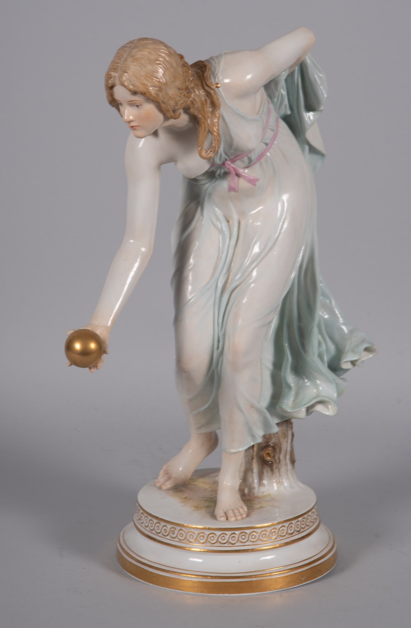 A Meissen Neo-Classical Style Porcelain Figure, the Bowler: A Meissen Neo-Classical Style Porcelain Figure, the Bowler A 14 1/4" tall Meissen figure of a semi-nude woman in a light blue draping gown throwing a golden ball. Blue cross swords mark, incised 