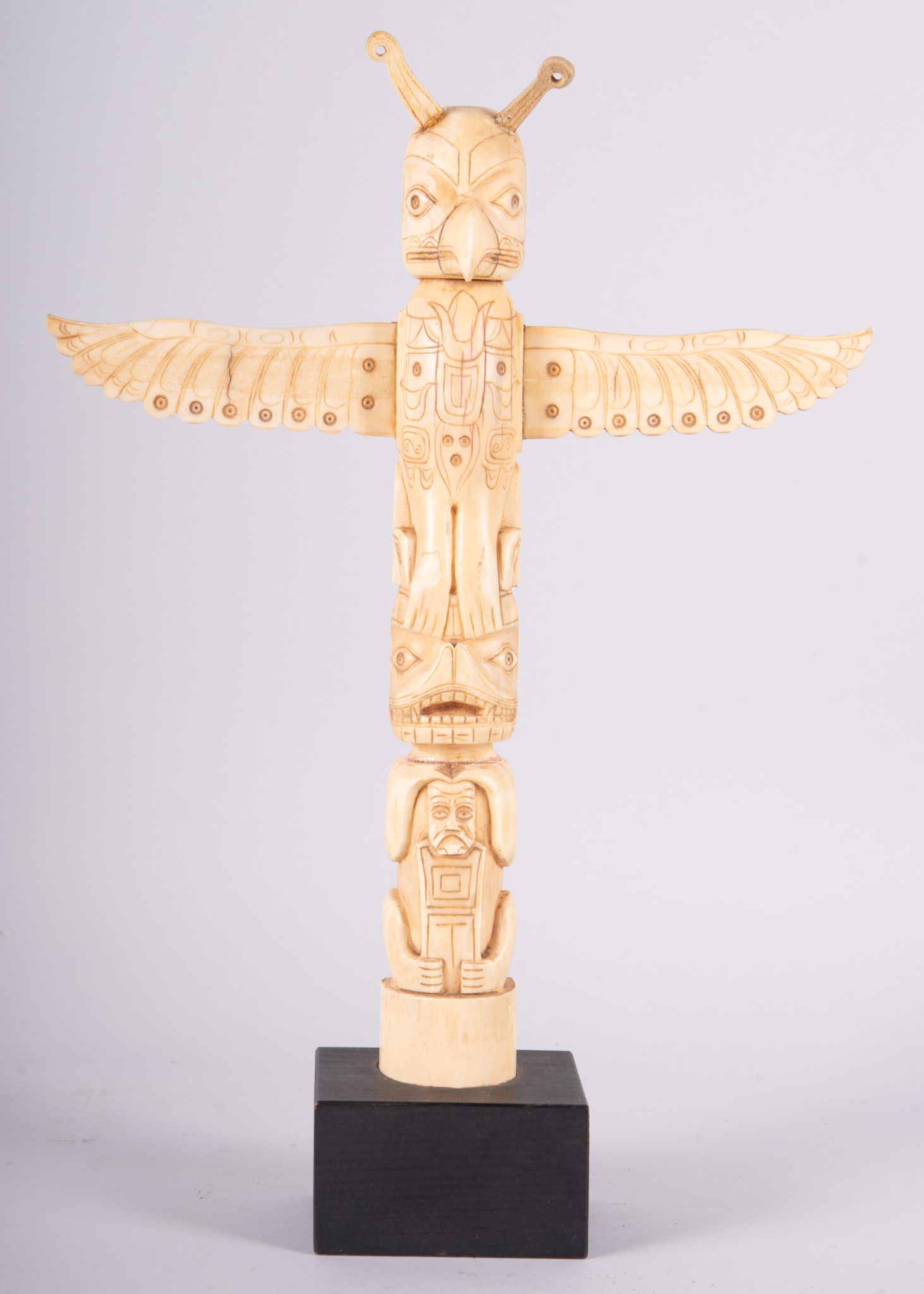 A Fine Early 20th Century Carved Walrus Bone Totem: A Fine Early 20th Century Carved Walrus Bone Totem On wooden base, a finely detailed north-west miniature effigy carved bone totem. Totem 12 1/4 inches tall, 9 1/2 inches wide, 14 inches tall with bas