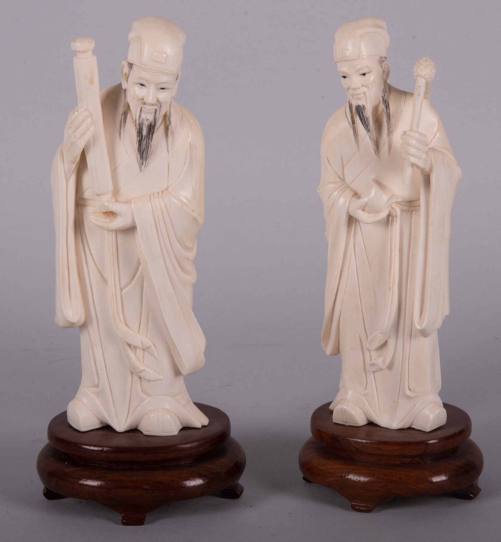 A Pair of Chinese Carved Bone Sculptures of Scholars: A Pair of Chinese Carved Bone Sculptures of Scholars On wood plinths, the pair of Chinese carvings depicting robed scholars. 7 inches tall, including stands.