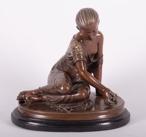 A Bronze Sculpture of a Seated Child Playing a Game