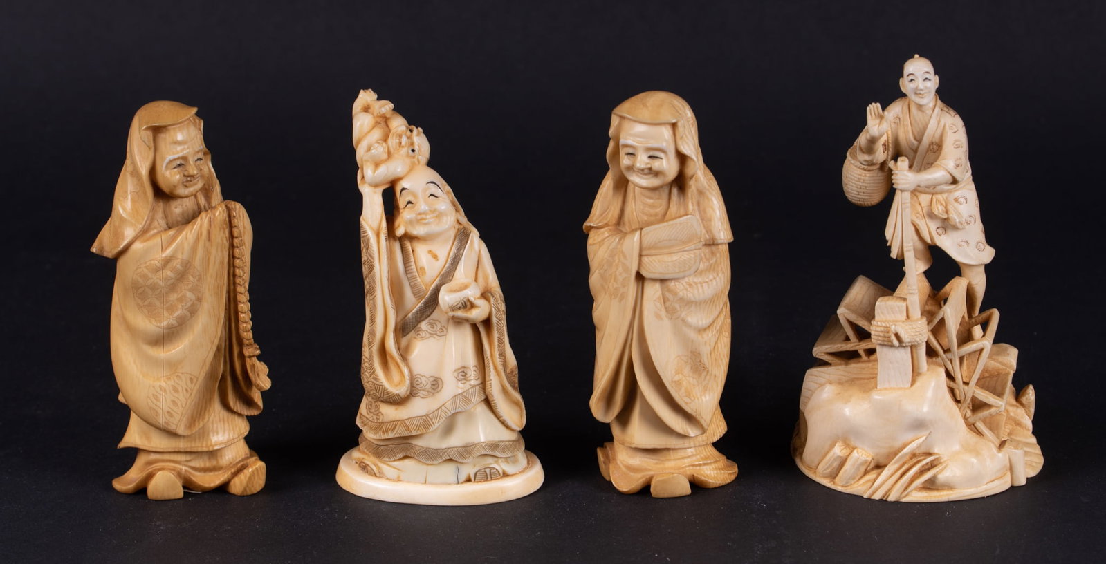 A Grouping of Four Japanese Okimono: A Grouping of Four Japanese Okimono Japan, mid-20th century, a grouping of diminutive bone carvings, one depicting a man on a waterwheel, and three of scholars. Tallest 4 1/2 inches