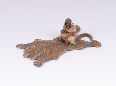 An Austrian Bronze Style Sculpture of a Man Seated on Lion Rug