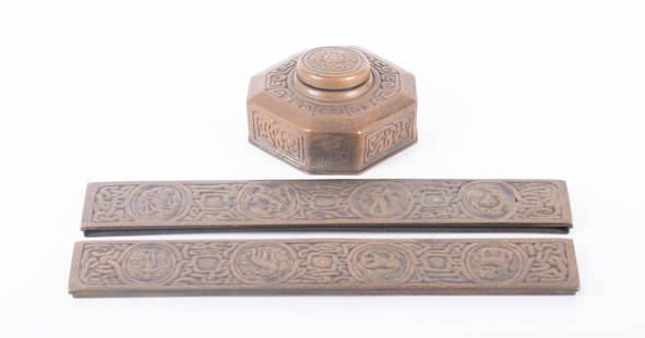 A Tiffany Studios Bronze Zodiac Pattern Inkwell and Desk Blotter Ends: A Tiffany Studios Bronze Zodiac Pattern Inkwell and Desk Blotter EndsNew York, the bronze inkwell with a crab to the lid marked Tiffany Studios New York 842 (4 inches square, 2 inches tall), with the