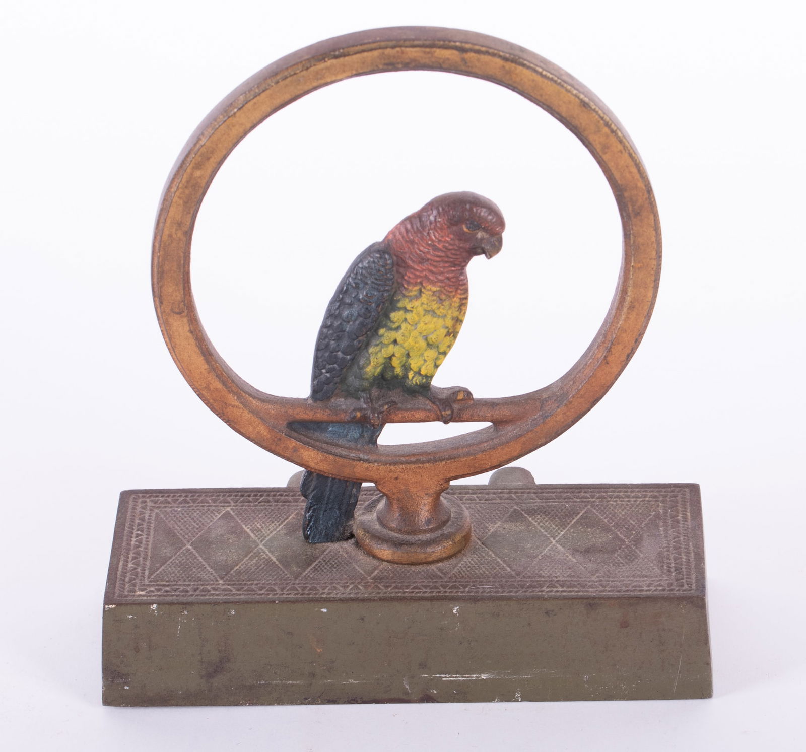A Cast Iron Parrot Doorstop: A Cast Iron Parrot DoorstopLikely Bradly and Hubbard, a painted parrot perched upon a circular frame.Provenance: The Estate of Diana Eley, St. Louis, MOWidth 7 inches, Height 8 inches, Depth 3 3/4 inc