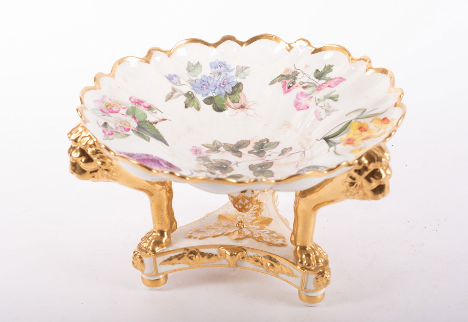 An Antique English Crown Derby Porcelain Center Bowl: An Antique English Crown Derby Porcelain Center BowlEngland, 19th century, the Derby centerpiece having a scalloped and shaped top with floral paintings, supported by three gilt monopod lions on a tri
