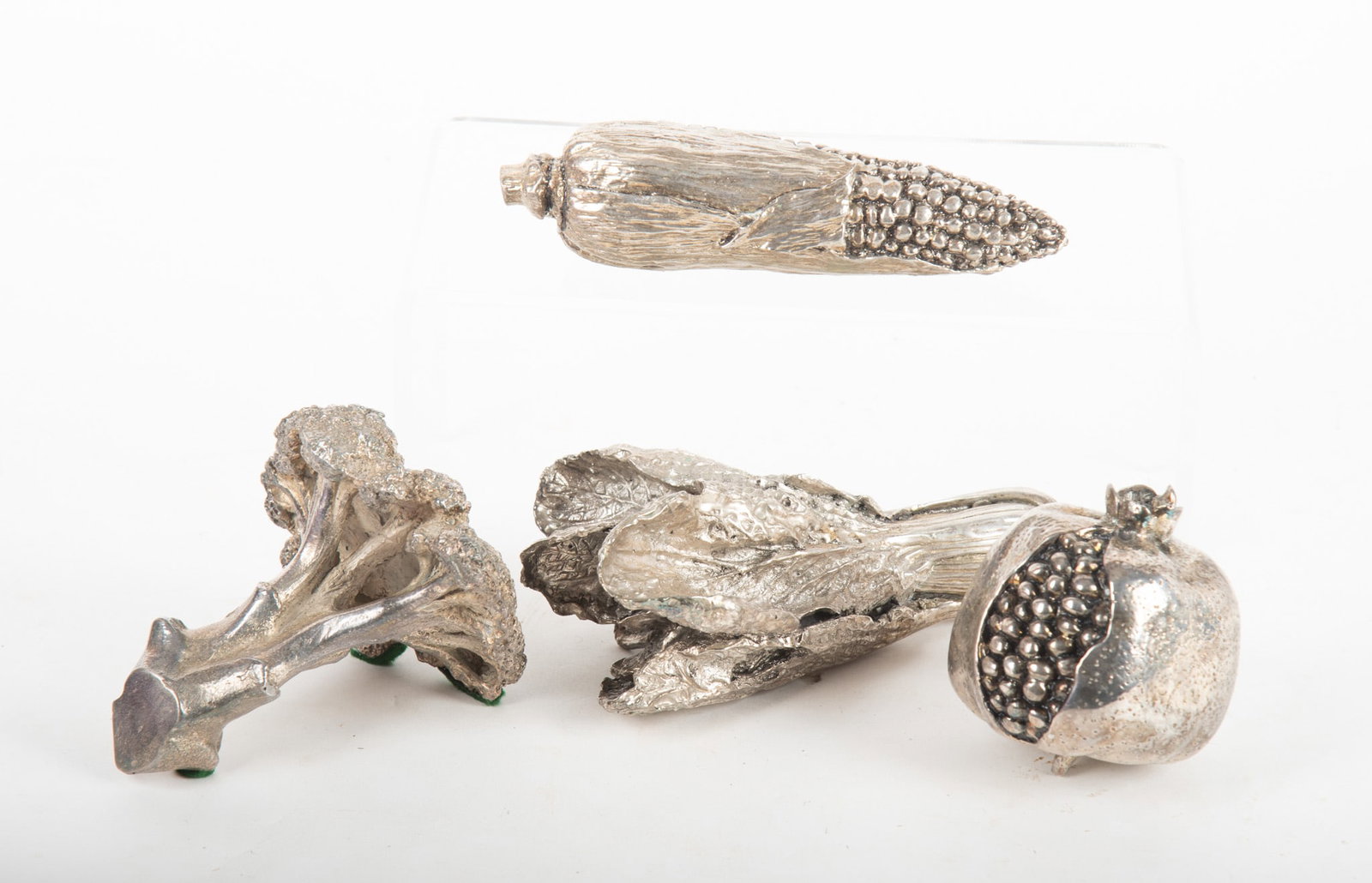 A Collection of Silvered Metal Vegetables and a Fruit: A Collection of Silvered Metal Vegetables and a Fruit The group includes a pomegranate, corn ear, broccoli, and a lettuce, unmarked. Provenance: The Estate of Diana Eley, St. Louis, MO Largest 3 3/4 x