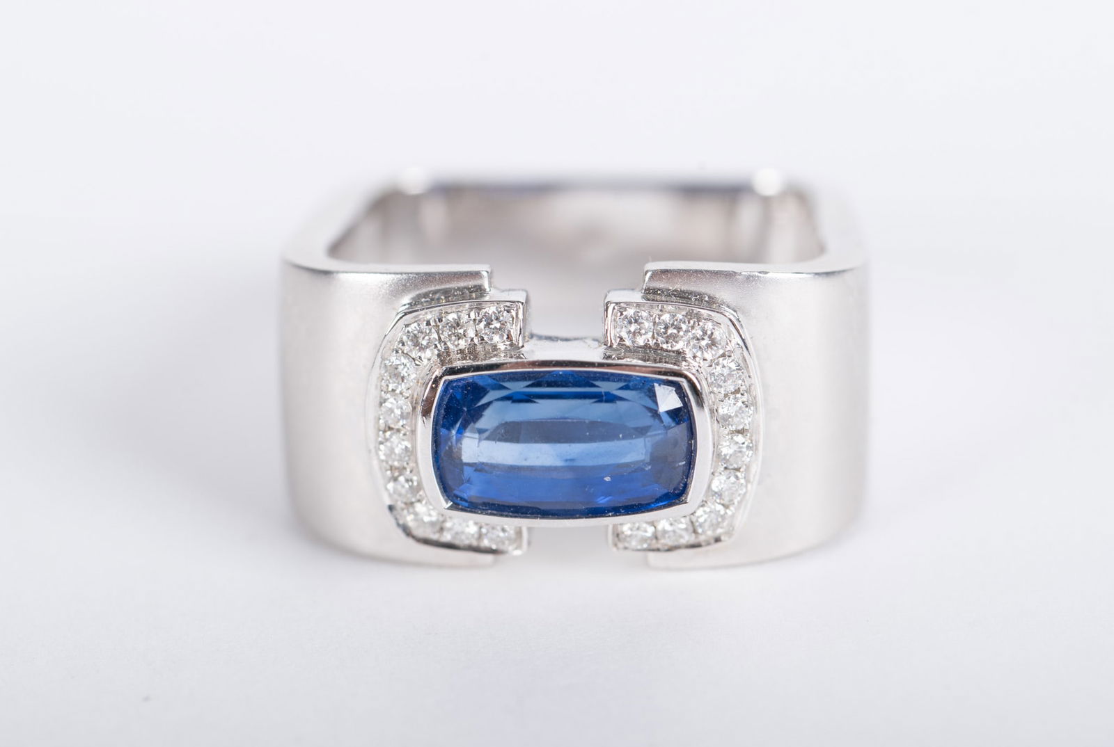 Handsome Barry Brinker Ceylon Blue Sapphire Ring: Handsome Barry Brinker Ceylon Blue Sapphire RingSet in 18K white gold with a row of diamonds embracing each side of the sapphire which measures 10.50mm x 6.50mm. The diamond weight is approximately .5