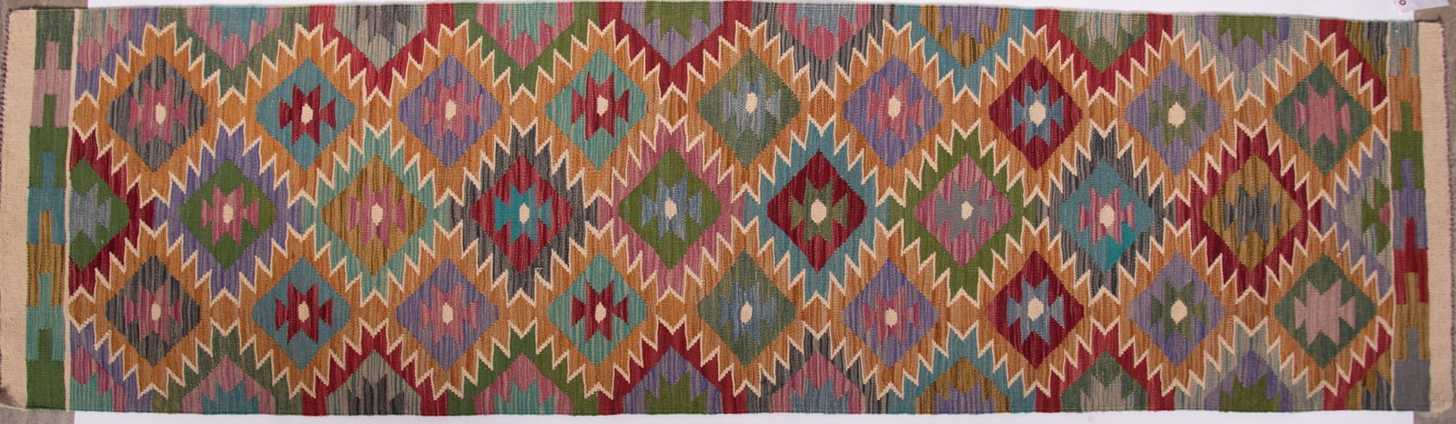 Hand Knotted Kilim Runner: Hand Knotted Kilim Runner Repetitive sawtooth diamond filled field in shades in green, tan, red, blue and ivory. 2' 9" x 9' 9"