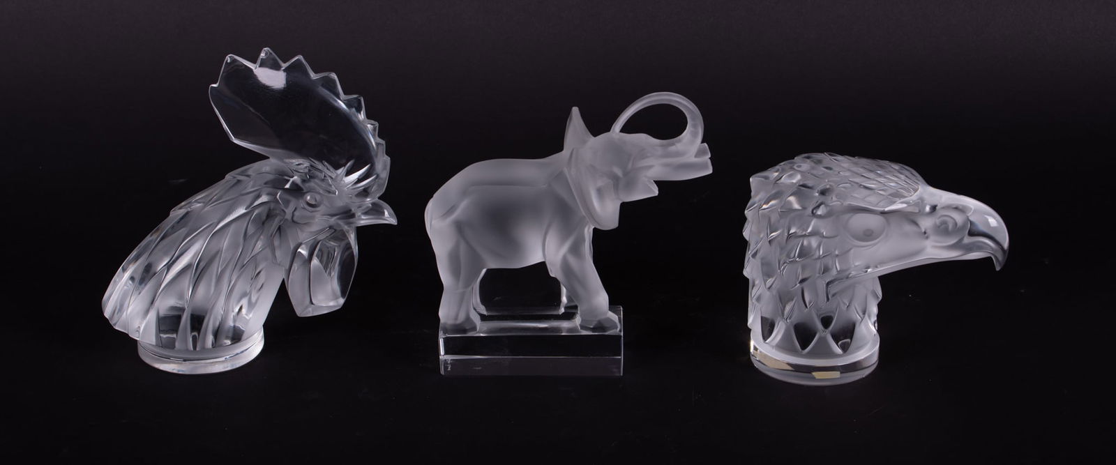 Three Lalique Crystal Animals: Three Lalique Crystal AnimalsFrance, late 20th century, two contemporary stylized car mascots or hood ornaments, Tete de Coq and Tete d'Aigle, one designed as a rooster head and the other as a eagle h