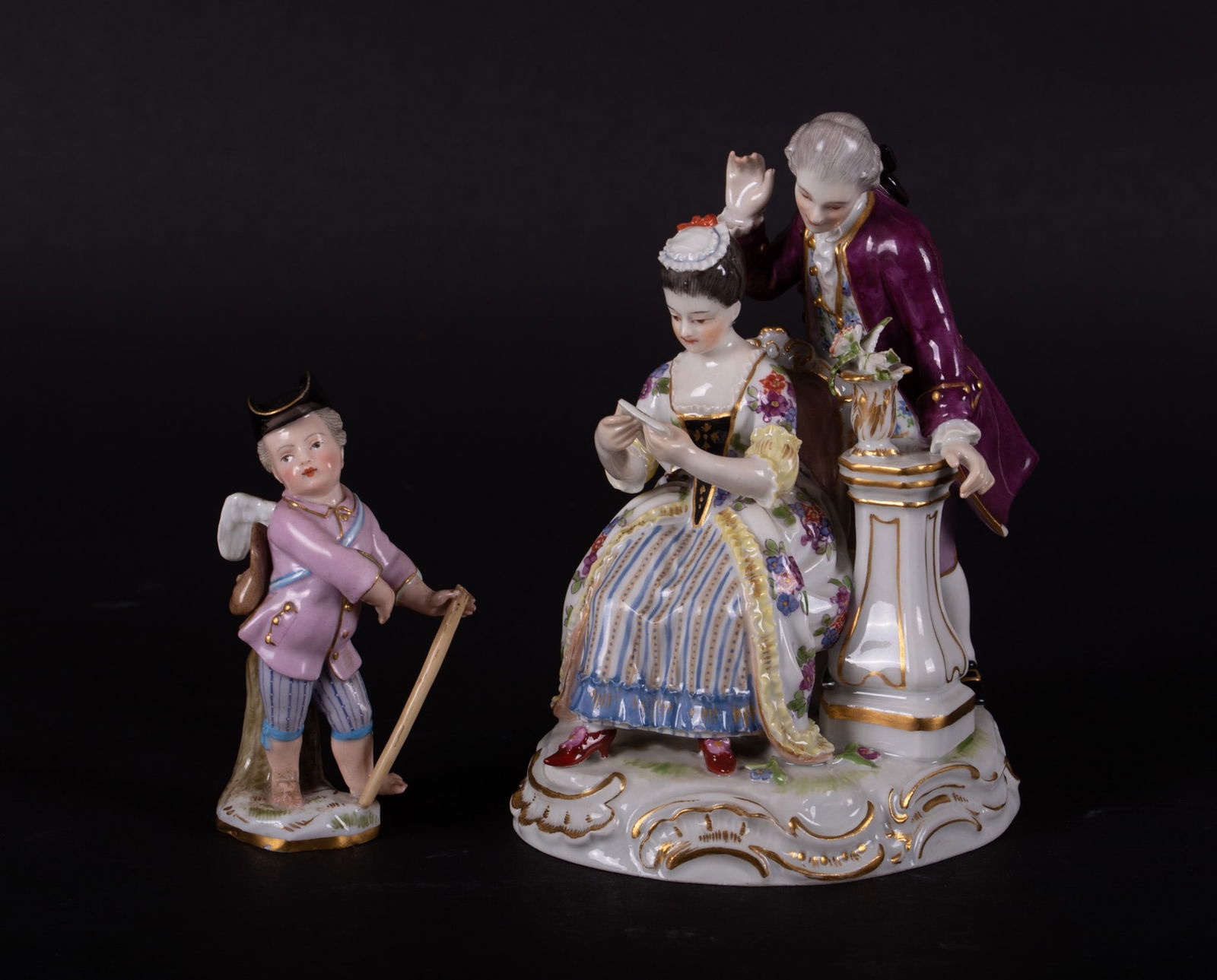 Two Meissen Figurines, Couple with Love Letter and a Cupid in Disguise: Two Meissen Figurines, Couple with Love Letter and a Cupid in DisguiseSmall Cupid figure has a hat, pink coat and striped pants and he is holding a walking stick. Couple designed by Sch?nheit, romanti