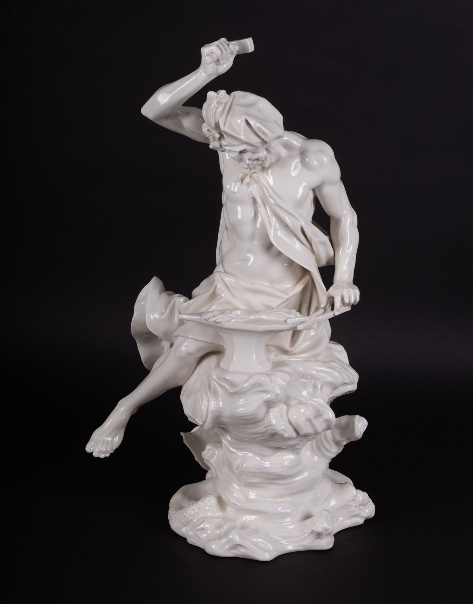 A Fine Nymphenburg Blanc de Chine Porcelain Figure, Emblematic of Vulcan: A Fine Nymphenburg Blanc de Chine Porcelain Figure, Emblematic of Vulcan Germany, 20th century, a finely detailed Nymphenburg sculpture of Vulcan, the figure seated on a rocky base at his anvil, one