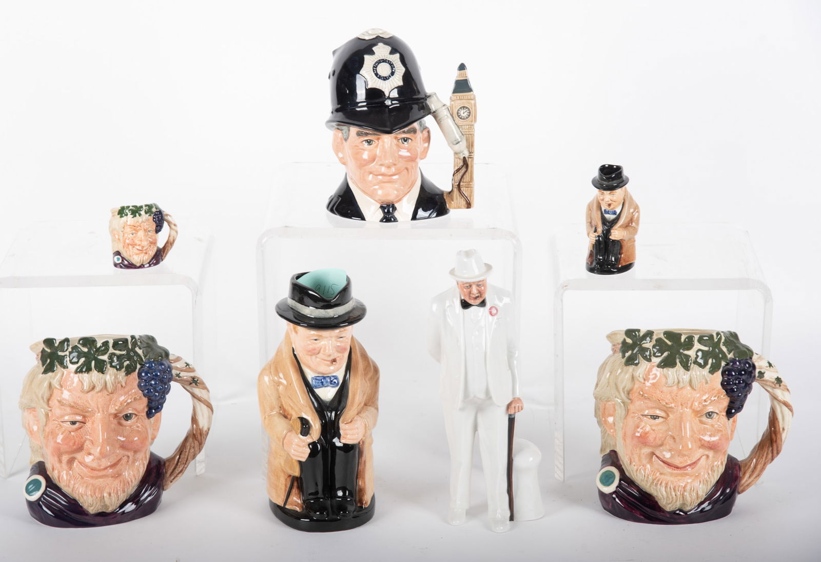 Royal Doulton Collection Including Winston Churchill Figure: Royal Doulton Collection Including Winston Churchill FigureSeven pieces. Winston Churchill HN3057 figure along with two Churchill mugs, Three Bacchus D6521, and two D6499, and The London Bobby D6744.
