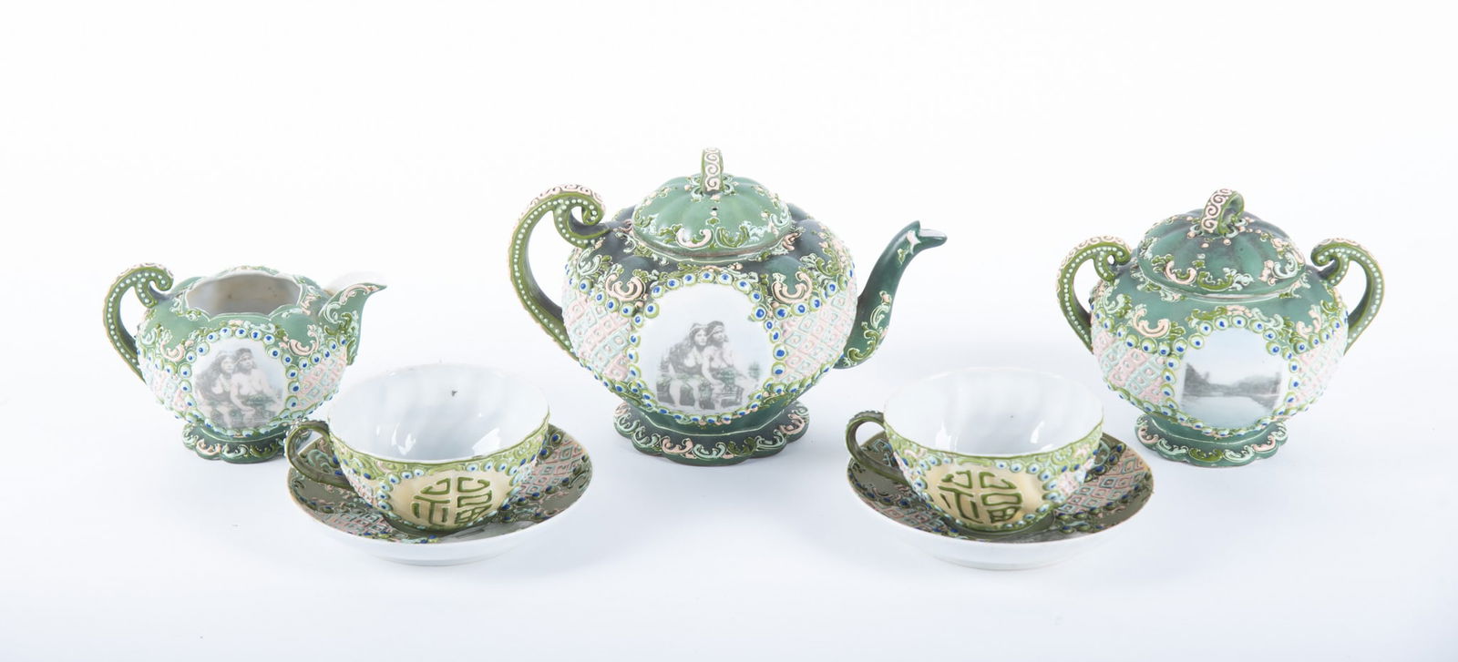 A Rare Japanese Moriage Tea Set, with Images of Hawaii and Semi-Nude Woman: A Rare Japanese Moriage Tea Set, with Images of Hawaii and Semi-Nude WomanJapan, early 20th century, an unusual Moriage Tete-a-Tete having heavily enameled and raised decoration on a green ground. Com