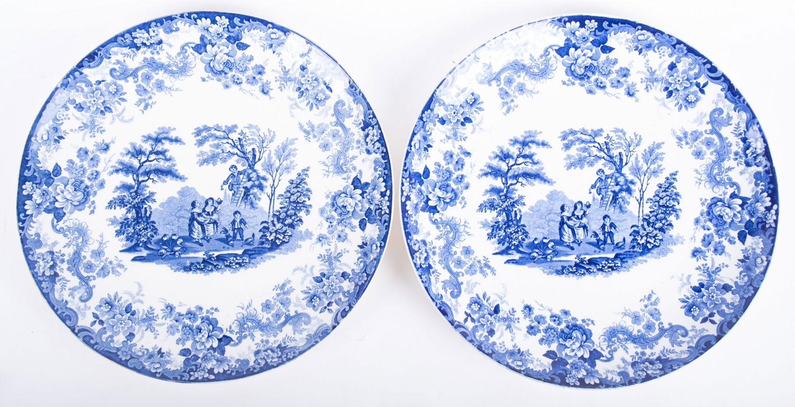 A Large Pair of Mintons Blue and White Chargers: A Large Pair of Mintons Blue and White ChargersEngland, late 19th century, the pair of flow-blue Staffordshire platters featuring young children picking fruit from a tree. Bears blue Mintons globe and