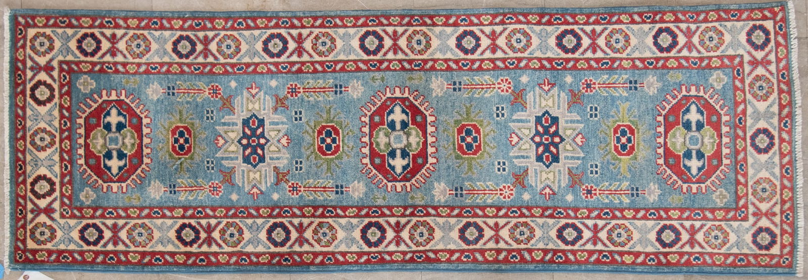 Handwoven Kazak Hall/Runner Rug: Handwoven Kazak Hall/Runner RugLight blue field with with five alternating elongated octagonal and geometric designs centering a repetitive floral border.2' 1" x 6'