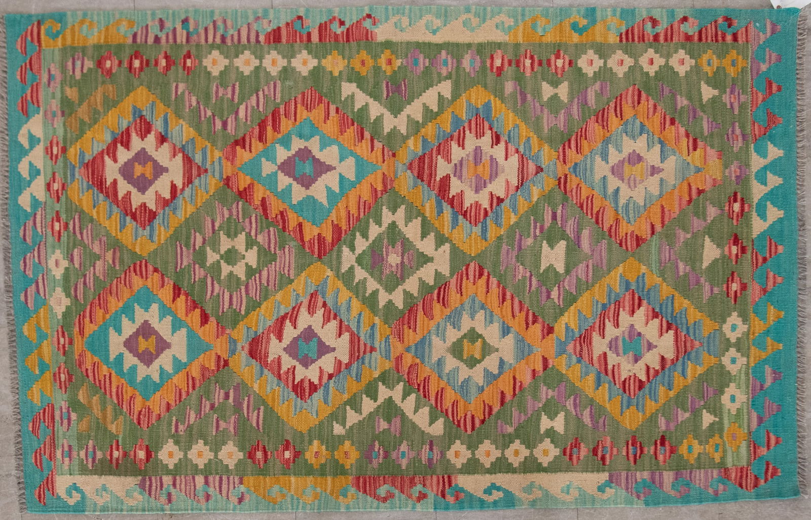 Handwoven Kilim Area Rug: Handwoven Kilim Area Rug The olive green field with a series of multi tiered diamonds in red, blue, cream and brown and a border with tribal symbols. 4' 2" x 5' 8"