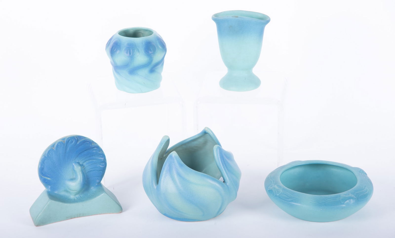 Van Briggle in Ming Blue: Van Briggle in Ming Blue Four pieces of Van Briggle glazed in Ming blue. Four signed pieces including a lotus leaf bowl, a low floral bowl, and a vase. Along with an unsigned peacock bookend in Van