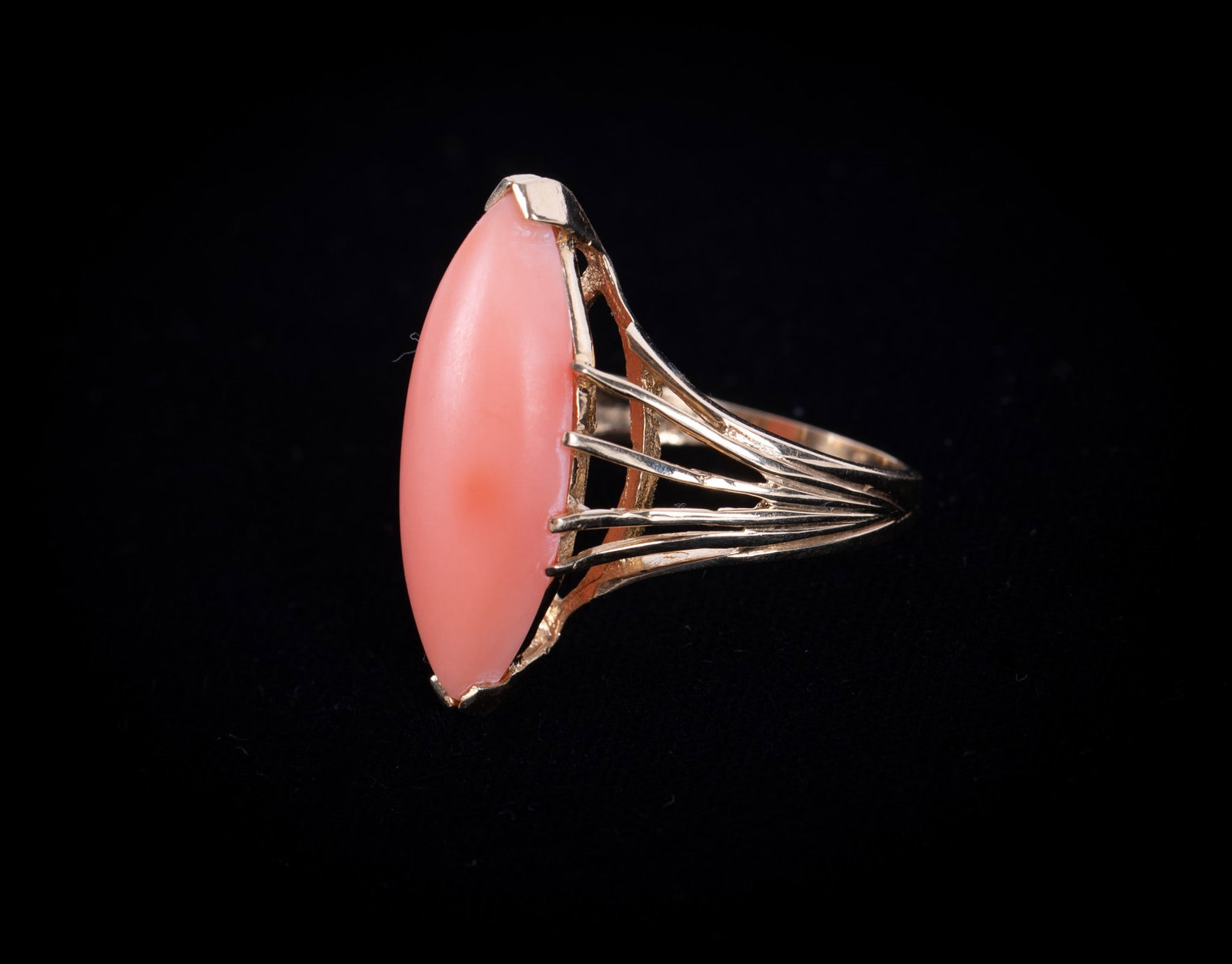 14K Yellow Gold Ring Set With a Coral Stone: 14K Yellow Gold Ring Set With a Coral StoneThis vintage ring has an interesting pronged mounting. The coral is marquise shaped and measures 24.60mm x 8.85mm. The stone could use a little polishing. We