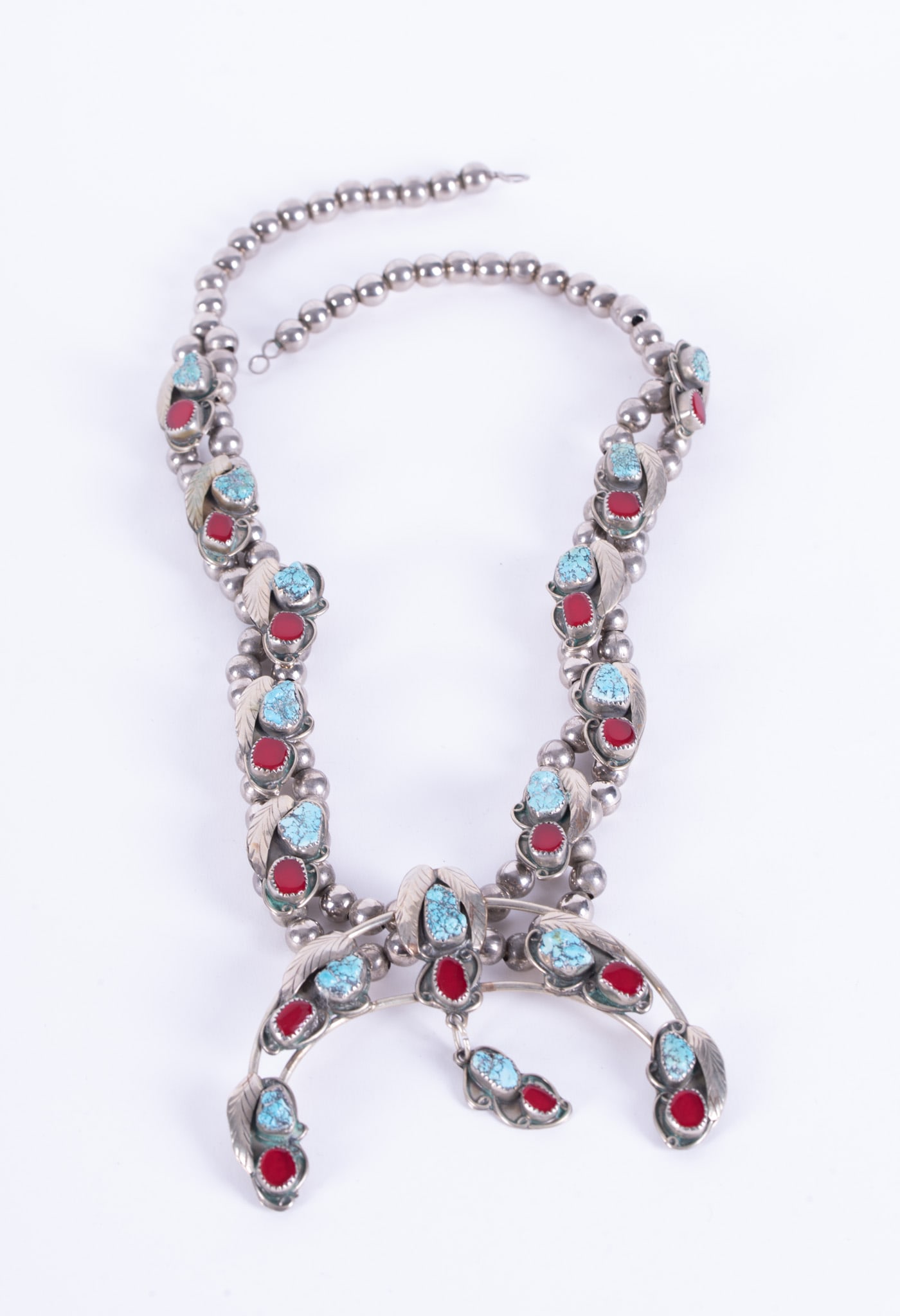 Native American Squash Blossom Necklace: Native American Squash Blossom NecklaceThis squash is nickle silver and is set with turquoise and red carnelian. The Naja measures 3 3/4 inches across, the length is 23 inches.