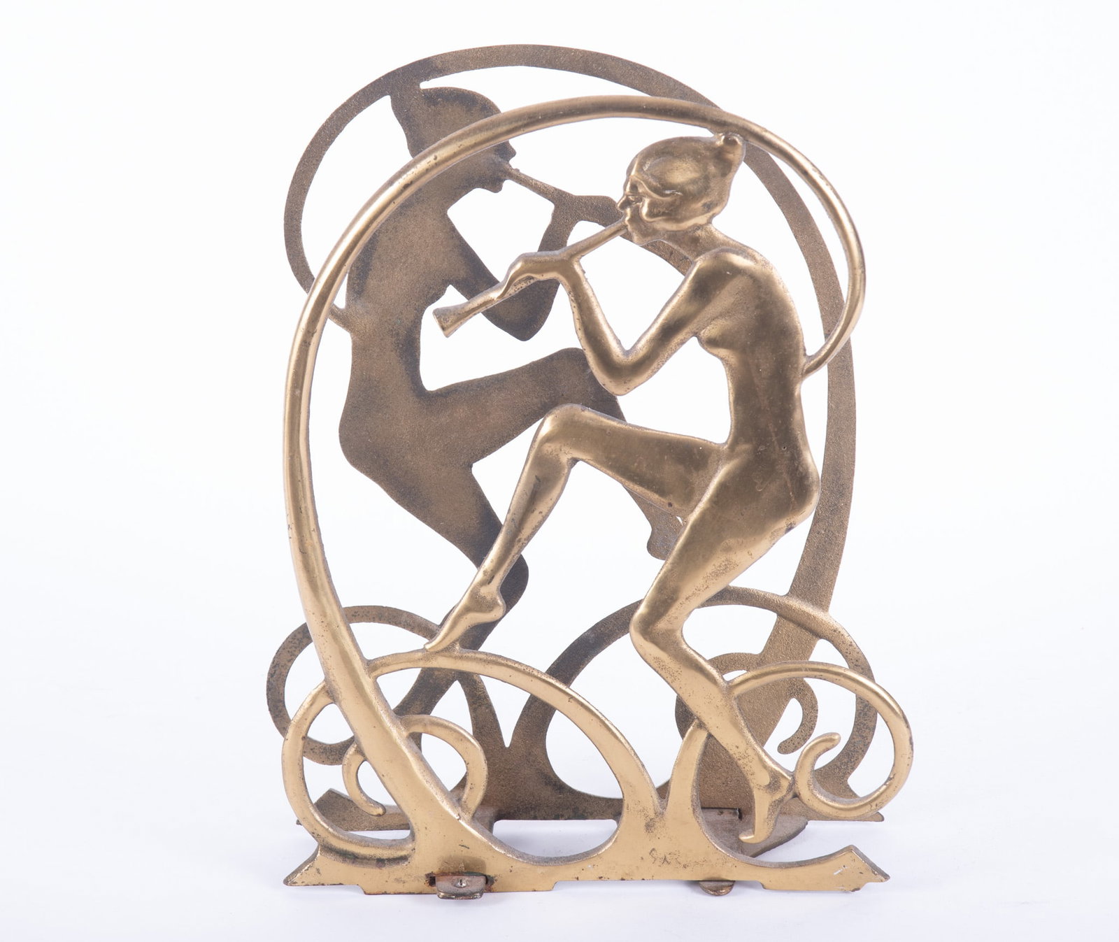 Seville Studio Art Deco Magazine Rack: Seville Studio Art Deco Magazine RackCirca 1928, Two flat-form nude figures playing the flute in profile, encircled by self-forming scroll frame mounted to adjustable brackets comprising base. Cast ir
