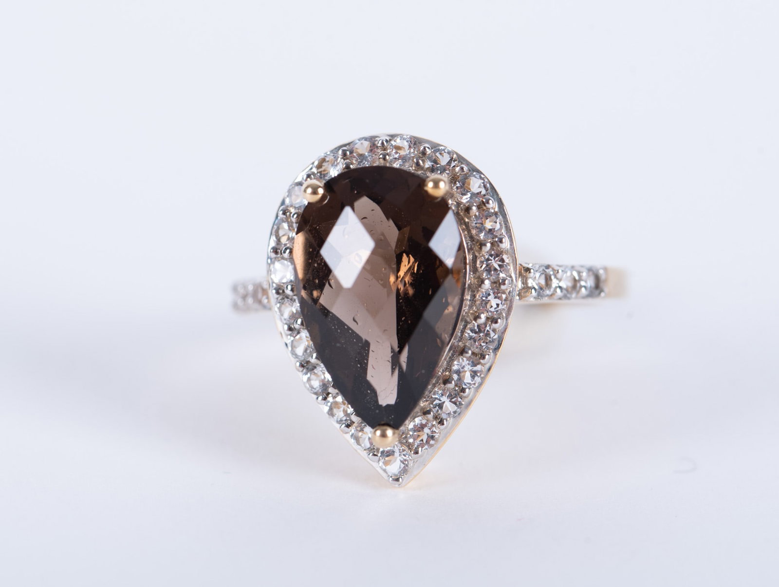 10K Yellow Gold Smoky Quartz Ring: The pear shaped quartz in this ring measures 9.30mm x 14mm. The surrounding stones are clear quartz. Ring size is 7 1/2 and the weight including stones is 4.4g.