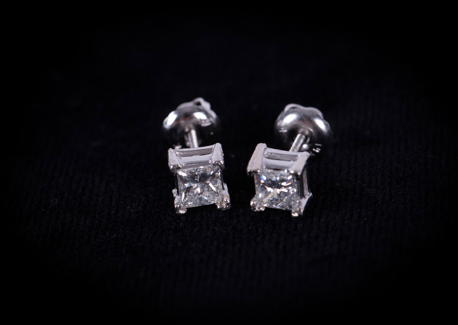 Ladies 14K White Gold and Diamond Studs: Diamond stud earrings set in 14k white gold marked on post. Each earring having a princess cut solitaire diamond weighing .33 CT set in four prong basket setting with screw back post. Gross weight 1.0