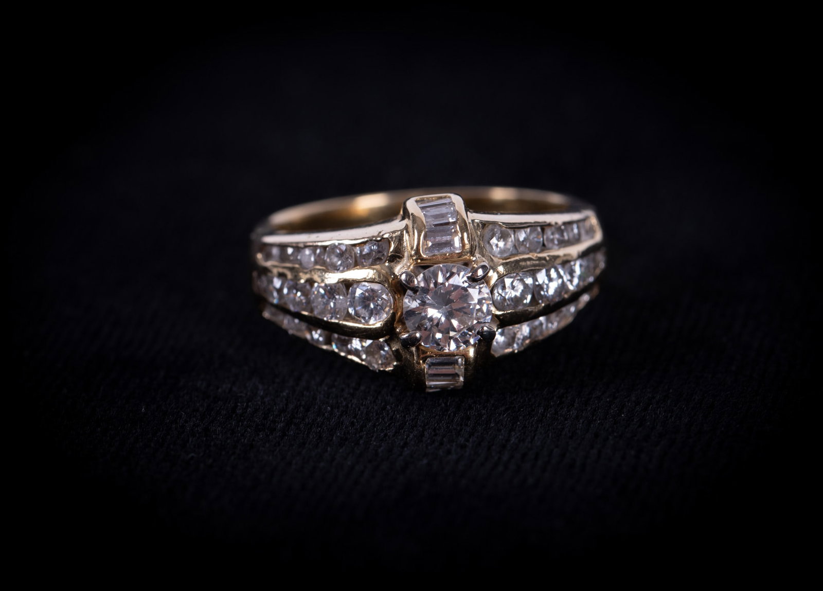 14K Yellow Gold and Diamond Engagement Ring: Ladies engagement ring of 14k yellow gold, marked KP. Round brilliant cut center stone with six channel-set baguette cut diamonds set north/south and 30 channel-set round brilliant cut diamonds in thr