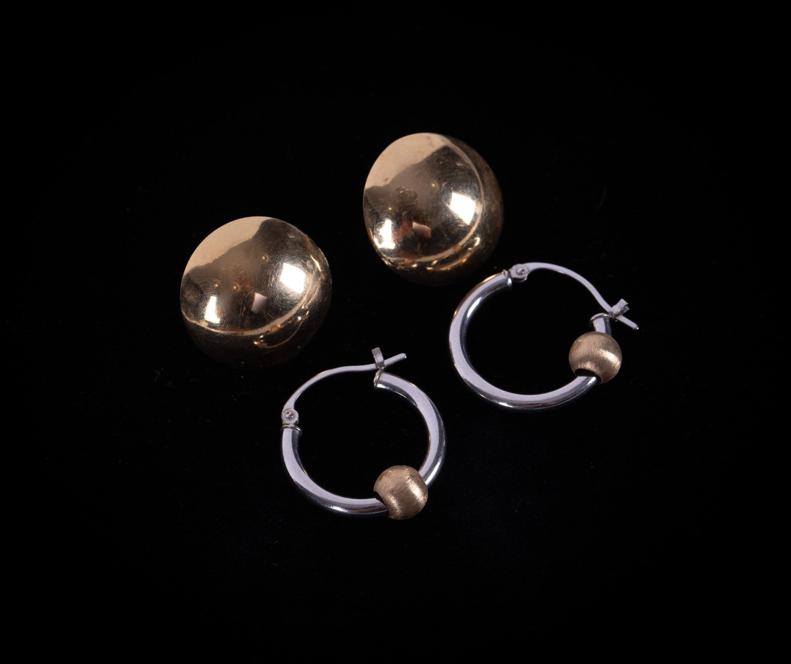 Two Pairs 14K Gold Earrings: First a pair of white gold hoop earrings with a yellow gold ball. They measure 18.8mm in diameter. Second pair are yellow gold. They are concave and 17.6mm in diameter.Total weight is 2.6g.