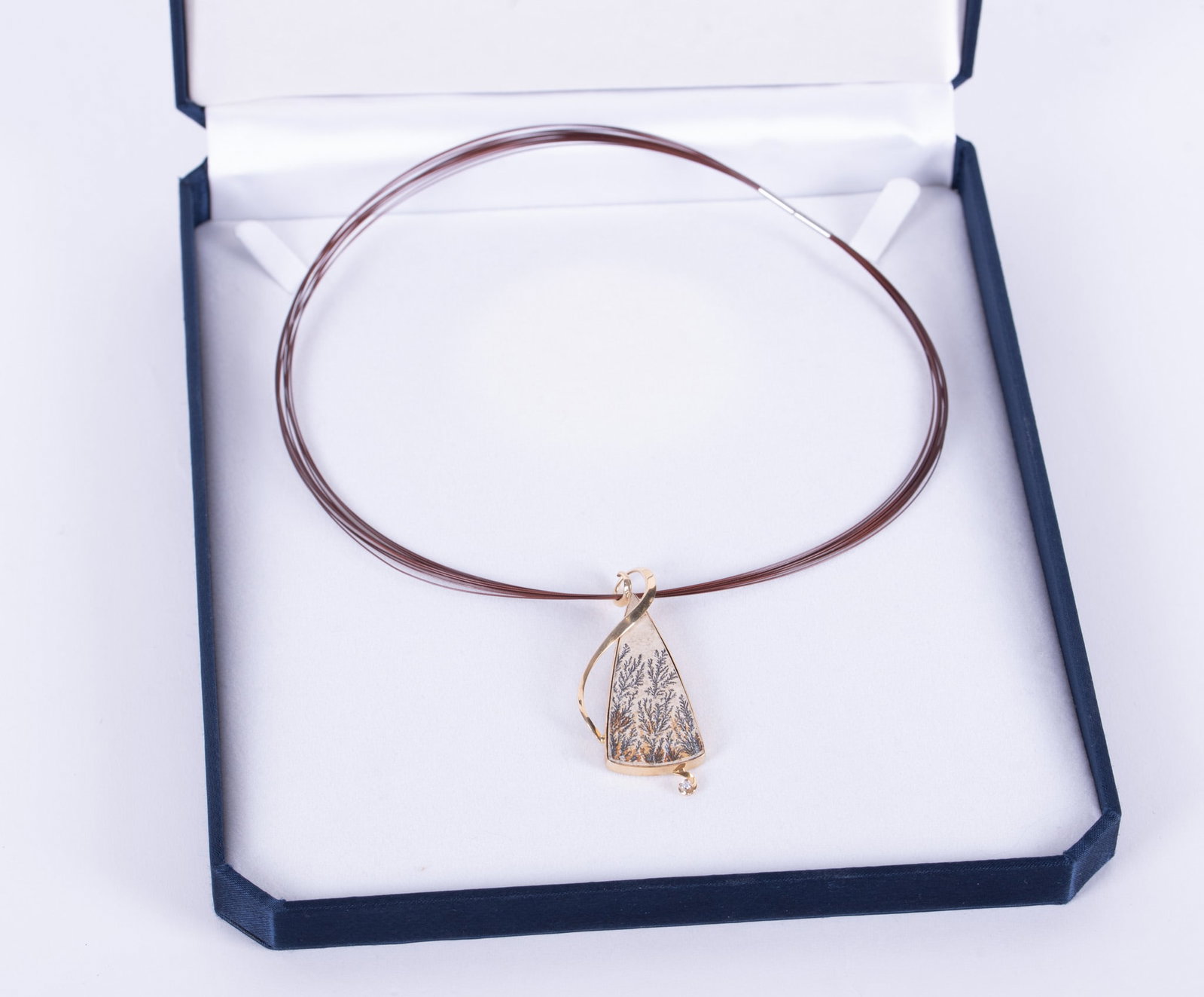 Unusual Psilomelane Dendrite Pendant set in 14K Yellow Gold: There is a ribbon of gold trailing across the stone and extends below the stone with a small diamond.Pendant hangs from a multi wire choker in a bronze tone. Weight of the pendant including the stone 