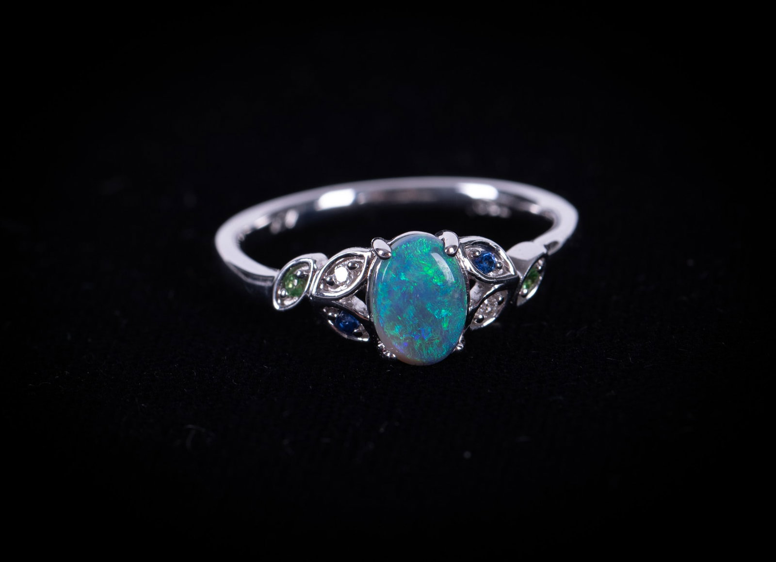 18K White Gold Opal Ring: The opal in this ring measures 6.95mm x 4.75mm. There are 3 multi colored stones on each side of the opal-sapphire, emerald and diamond. Ring size is 7 and the weight including stones is 3.1g.