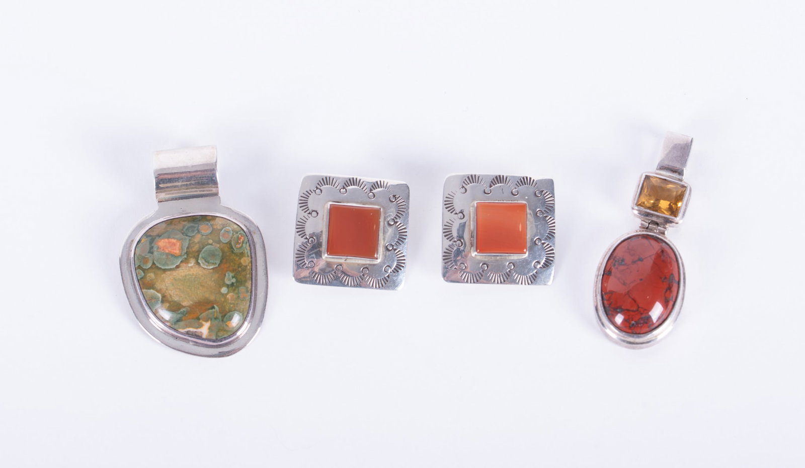 Two Sterling Stone Pendants; One by Citlal Castillo-signed Sterling Earrings Included: The clip back earrings are signed NEZ and are set with what appears to be carnelian. The Castillo pendant is set with a polished Rainforest Jasper, also known as green Rhyolite. The stone measures 1 x