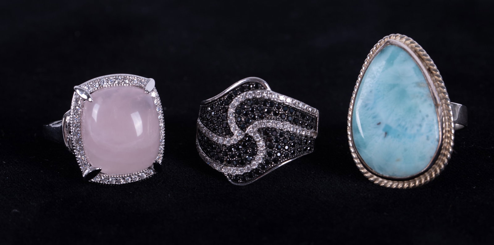 Three Sterling Rings with Stones: First a lovely rose quartz ring surrounded by glittery stones. It is size 8. Next is a ring set with a Larimar stone measuring 23.80mm x 15.80mm. It is also size 8. Last of all we have a ring pave' se