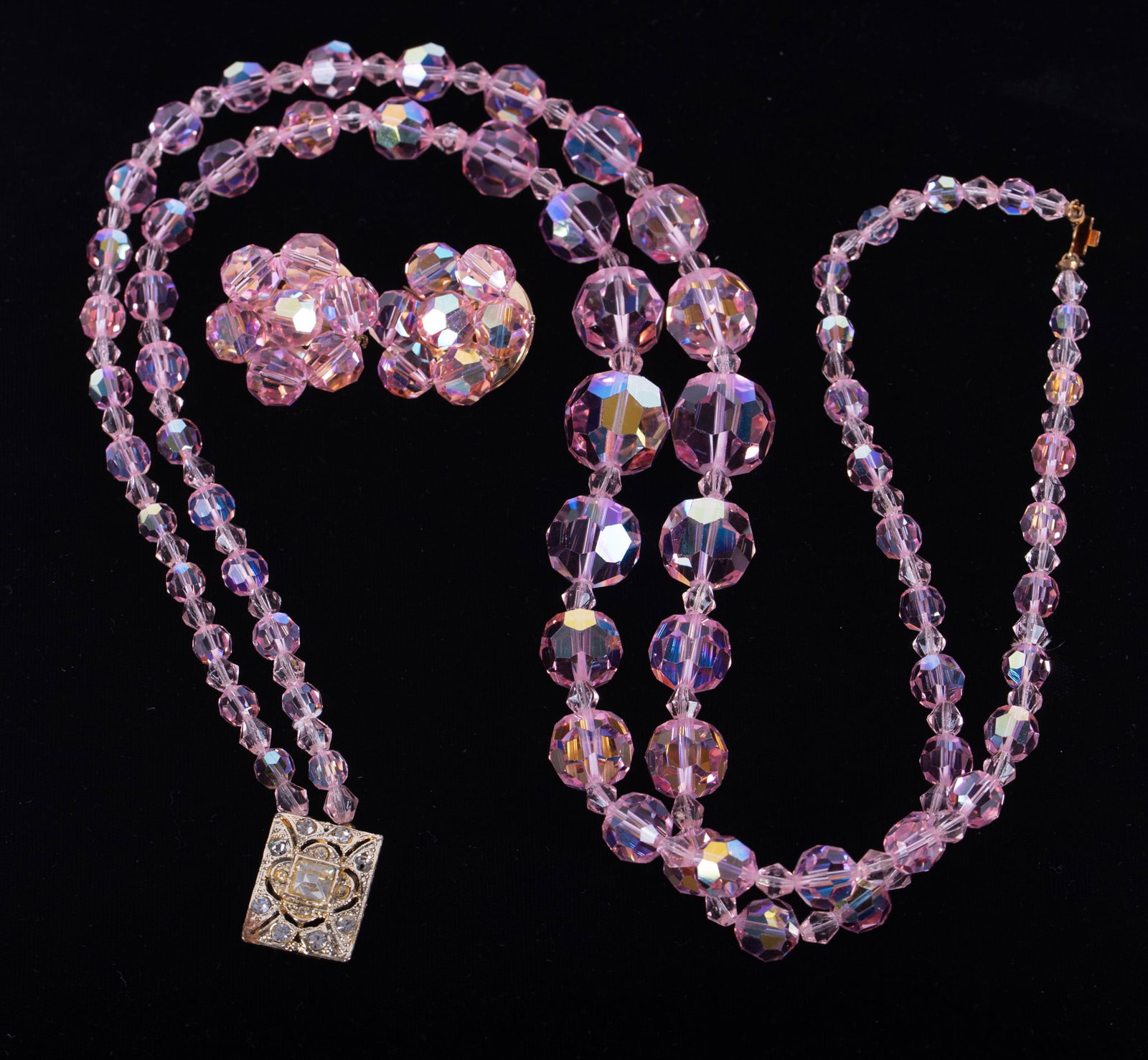 A Pink Crystal Graduated Bead Double Strand Necklace with Rhinestone Clasp and Matching Pair of: The pink crystal bead necklace with rhinestone clasp, length 18 inches, with matching pair of clip-on earrings; together with a Vintage clear crystal bead double strand necklace, unmarked, length 30