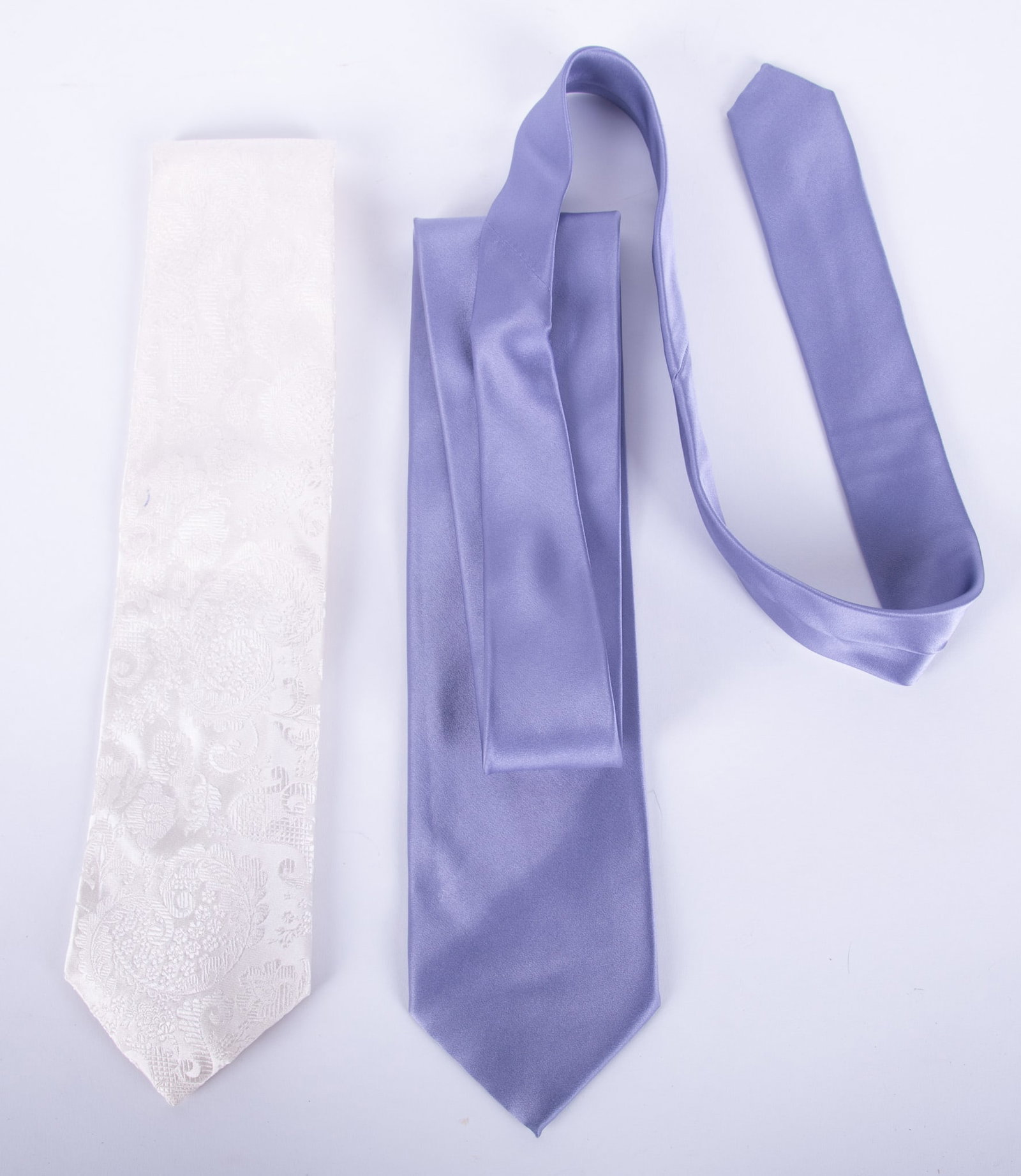 Two Designer Dress Ties by Brioni and Paul Smith: one Brioni lavender solid color, 100% silk, Made in Italy; together with one Paul Smith white-on-white 100% pure silk textured tie with cornucopia design, Made In England. Excellent condition.