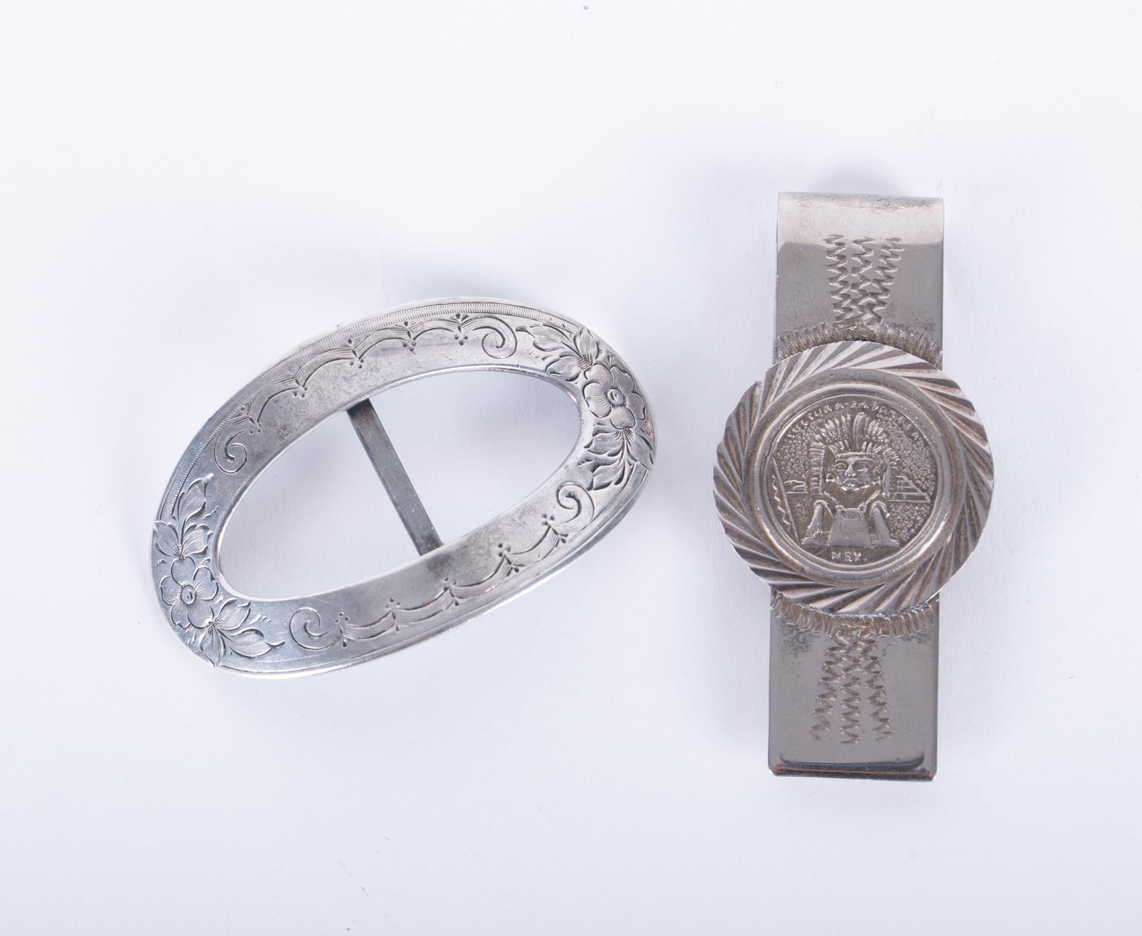 Sterling Silver Money Clip and Buckle: money clip with round Egyptian head decoration, 2 1/2 x 3/4 inches; oval buckle engraved with floral decoration, 2 1/2 x 1 3/8 inches; total weight 0.935 troy ounces.