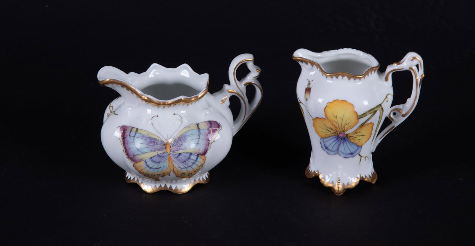 Two Anna Weatherly Porcelain Creamers: Hungary, one of the cream jugs having a pansy pattern to the front and large butterfly to the reverse, the other cream jug featuring a large butterfly to the front and a ivy leaf pattern to the revers