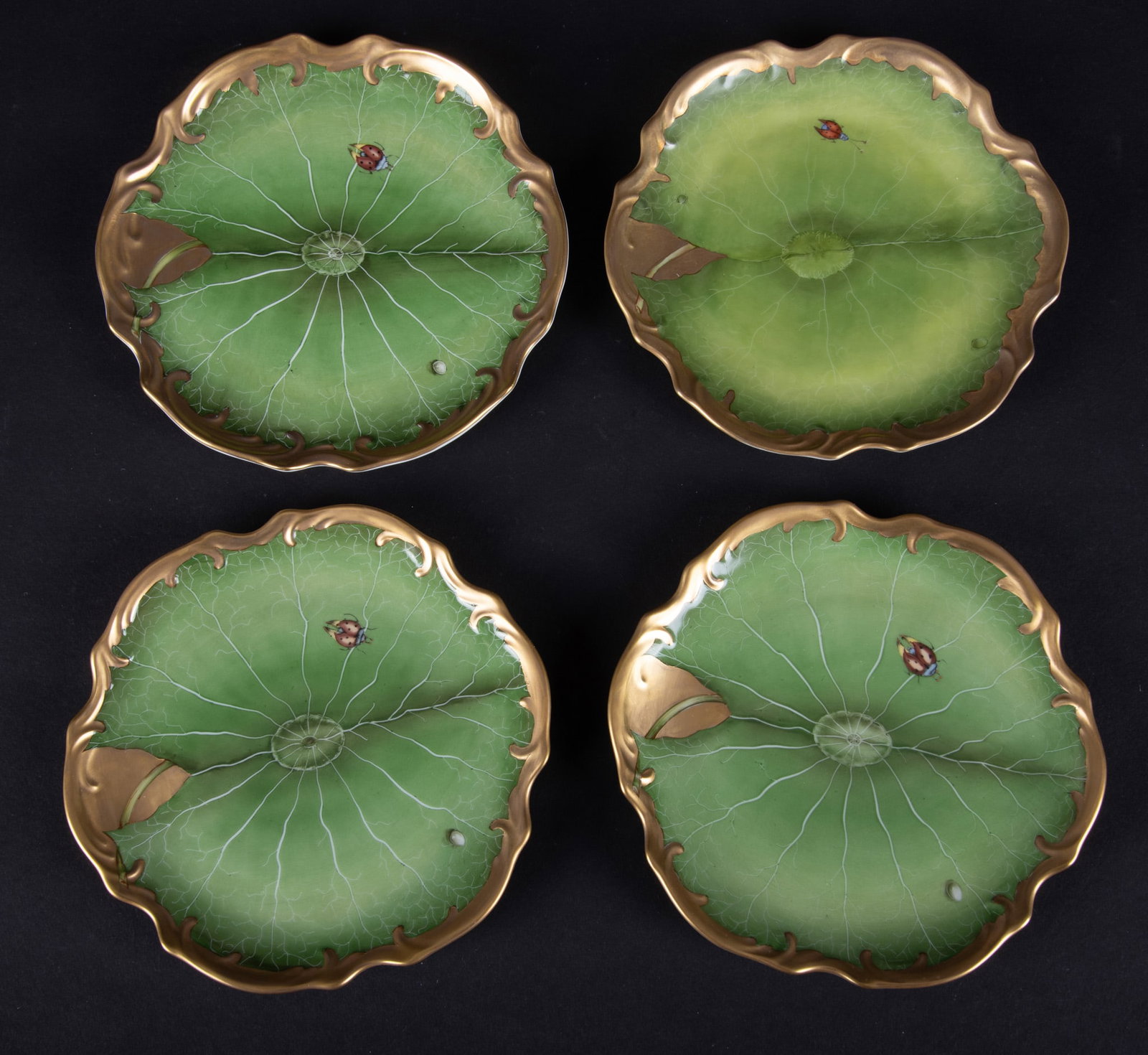 Four Anna Weatherley Porcelain Bread and Butter Plates, Ivy Garden: Hungary, four hand painted plates with heavy gilt borders, the large green leaf supporting a lady bug and small snail. Although the same pattern, the plates were collected at different times and show 