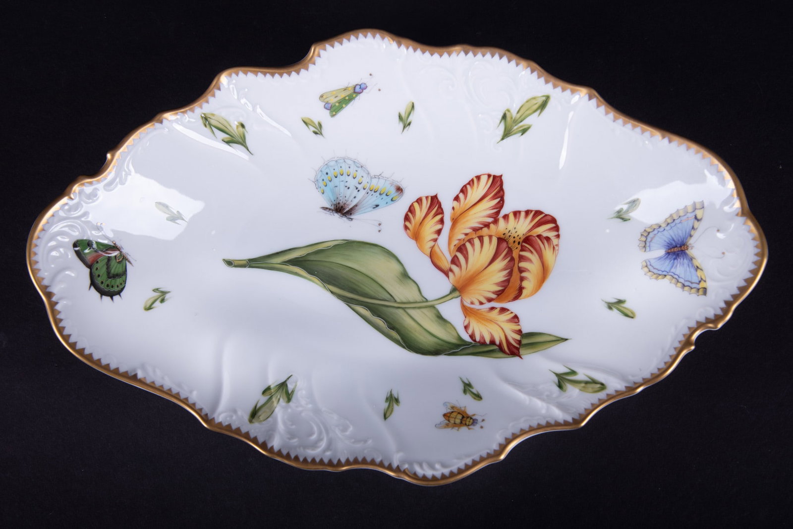 An Anna Weatherley Elongated Serving Bowl, Old Master Tulips Pattern: Hungary, a hand painted porcelain bowl having a yellow/orange tulip surrounded by butterflies and insects. This piece carries an unusual corn husk design.