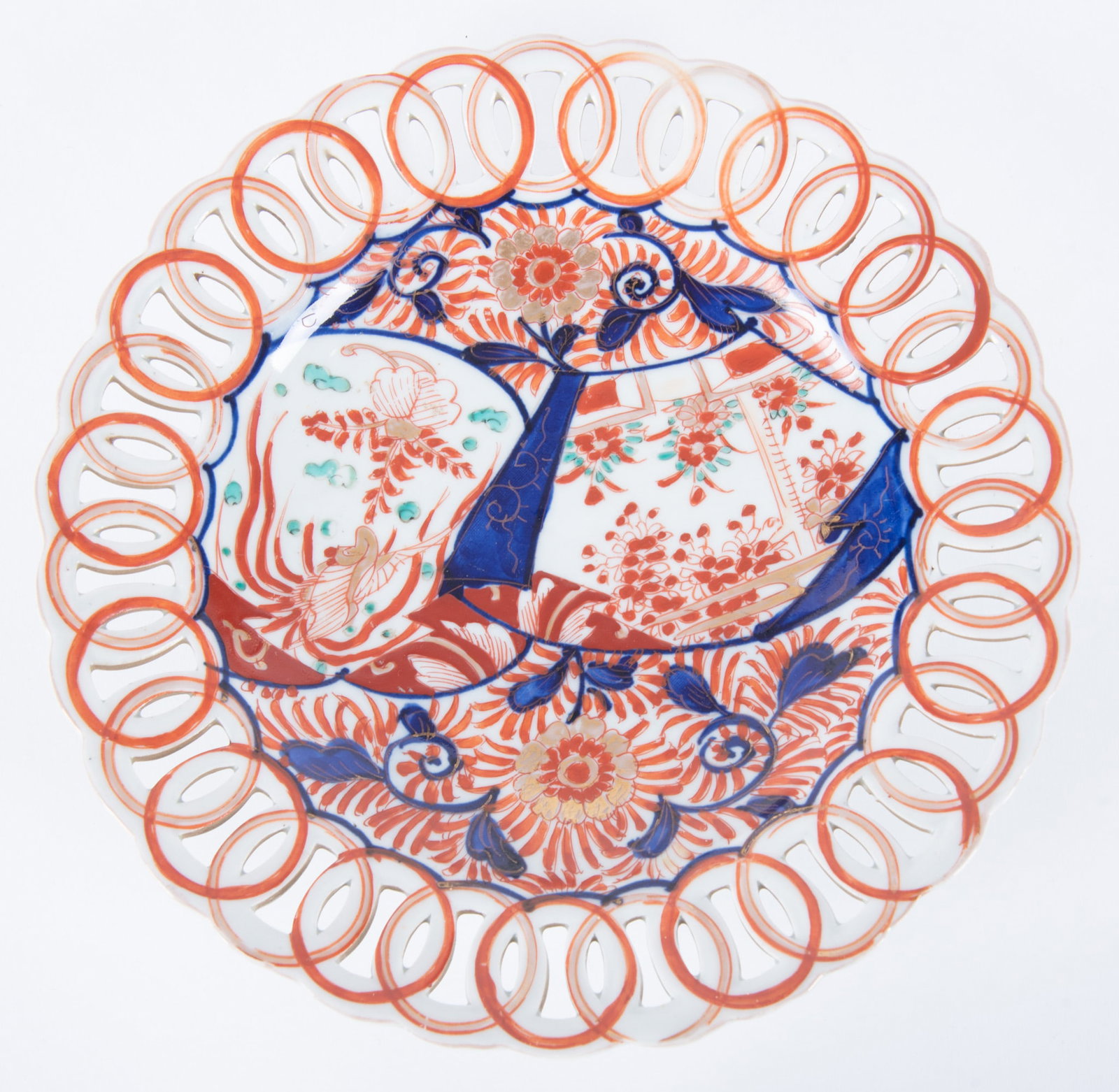 An Antique Imari Porcelain Reticulated Charger Plate: Meiji period, the hand-cut pierced rim plate featuring traditional Imari color palette of iron red, blue, green and gilded accent; the plate's central well design of intricate painted fan and floral m