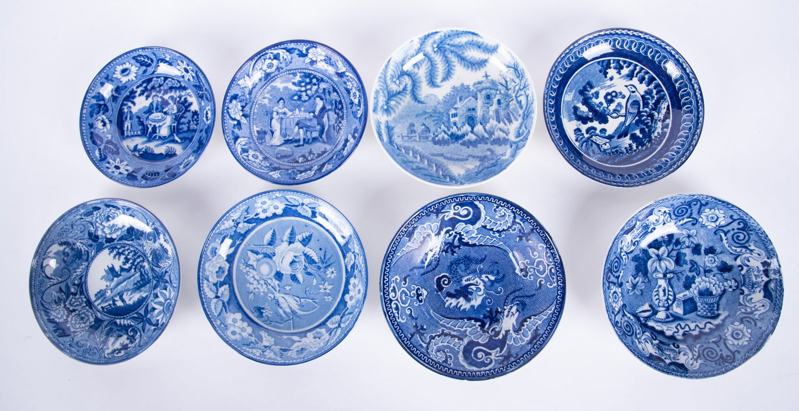 A Collection of Eight Antique Staffordshire Tea Saucers: England, early 19th century, an unusual 4-toe dragon saucer (rim chip, 2 small base chips, 1 glaze nick), a pheasant perched in flower and fruit branches, a Clews bowl featuring botanicals in vases;