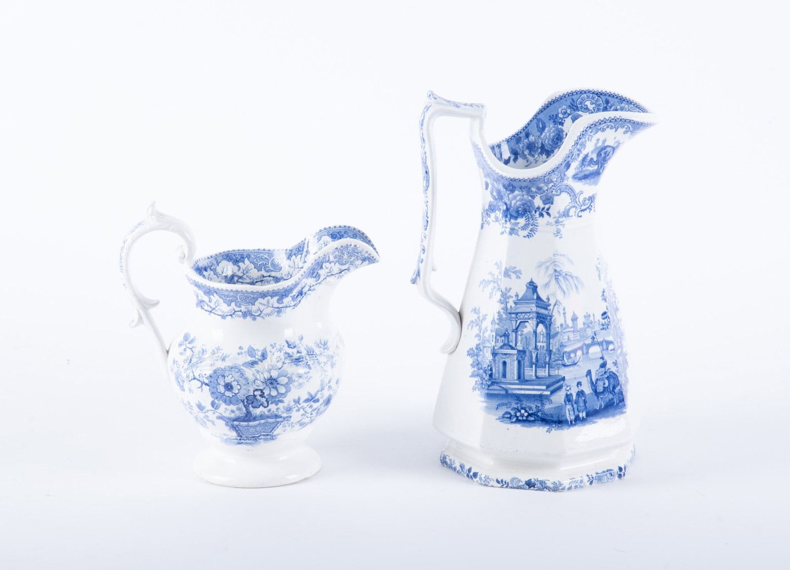 Two Antique Staffordshire Transferware Pitchers: England, mid-19th century, by Podmore, Walker & Co, a 12 1/4 inch tall Pearlware pitcher in the Asiatic Views pattern featuring figures on camels against a lavish Mughal setting of palaces and botanic